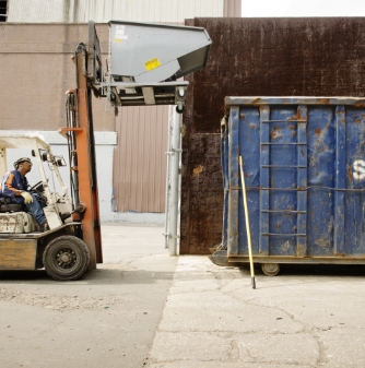 worker-moving-container-with-forklift-at-recycling-2022-05-25-04-50-44-utc